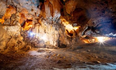 Cave exploration scene in Halong Bay with stunning rock formations and warm sunlight.