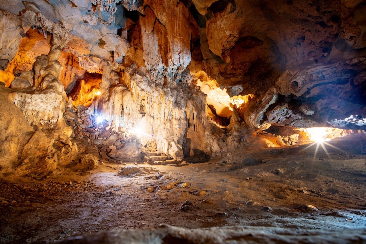 Cave exploration scene in Halong Bay with stunning rock formations and warm sunlight.