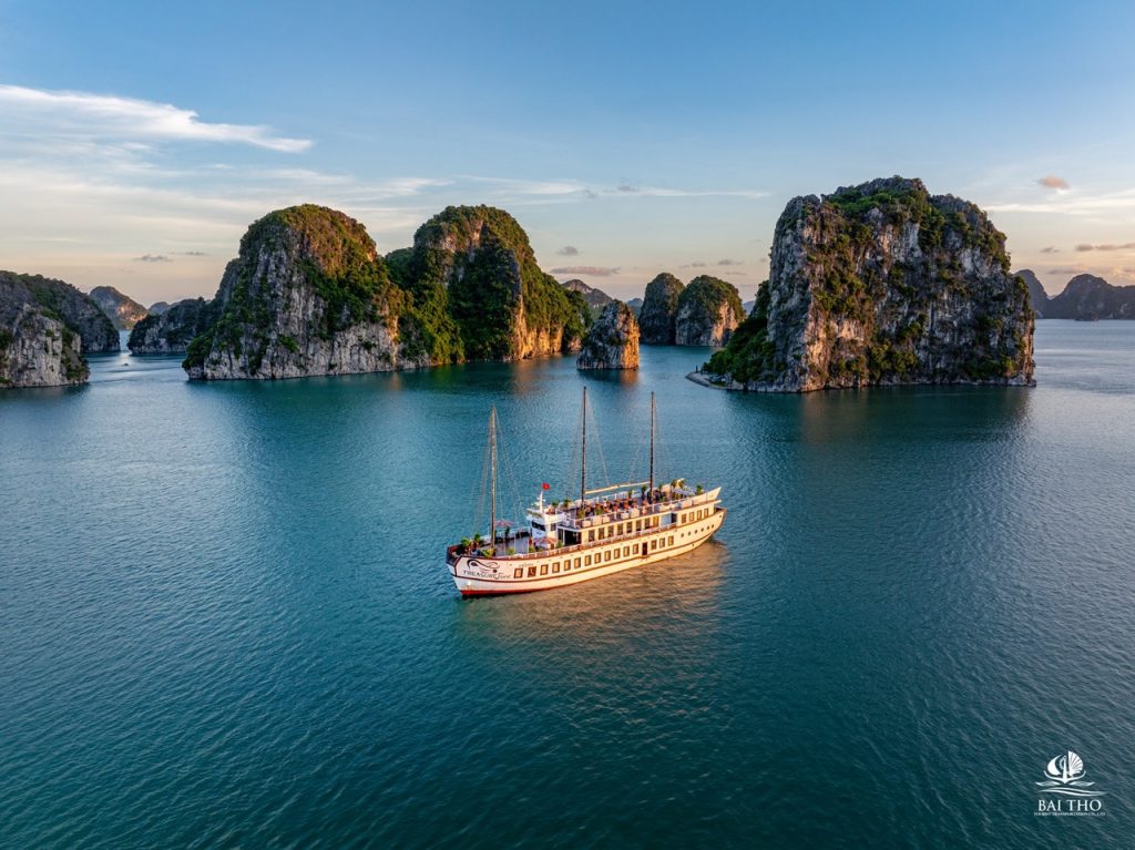 ViettrendTour cruise sailing through stunning limestone islands in Bai Tu Long Bay at sunset, perfec.