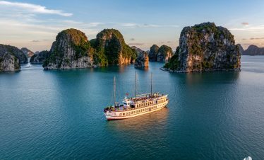 ViettrendTour cruise sailing through stunning limestone islands in Bai Tu Long Bay at sunset, perfec.