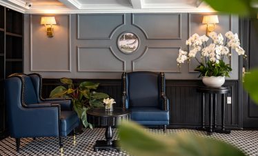 Elegant cruise lounge with navy blue armchairs and floral decor in Halong Bay. Perfect for relaxing.