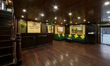 Interior of a luxurious cruise lounge with wooden floors and green seating, showcasing a relaxing at.