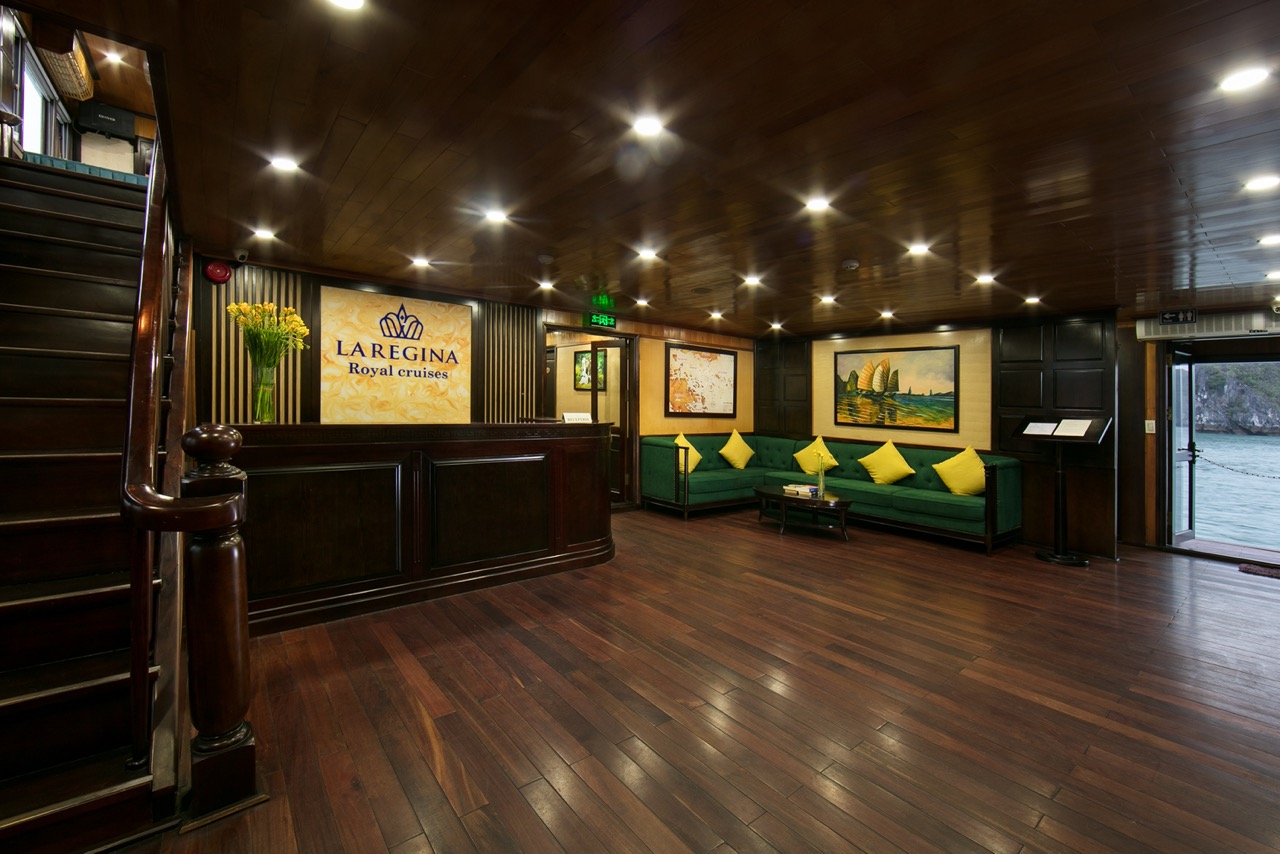 Interior of a luxurious cruise lounge with wooden floors and green seating, showcasing a relaxing at.