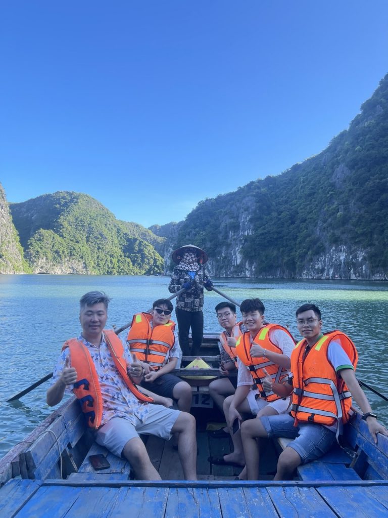 Kayaking in Halong Bay with stunning mountain backdrop, group enjoying scenic cruise and tranquil wa.