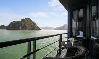 Scenic view of Halong Bay from a luxury cruise balcony with calm waters and lush islands.