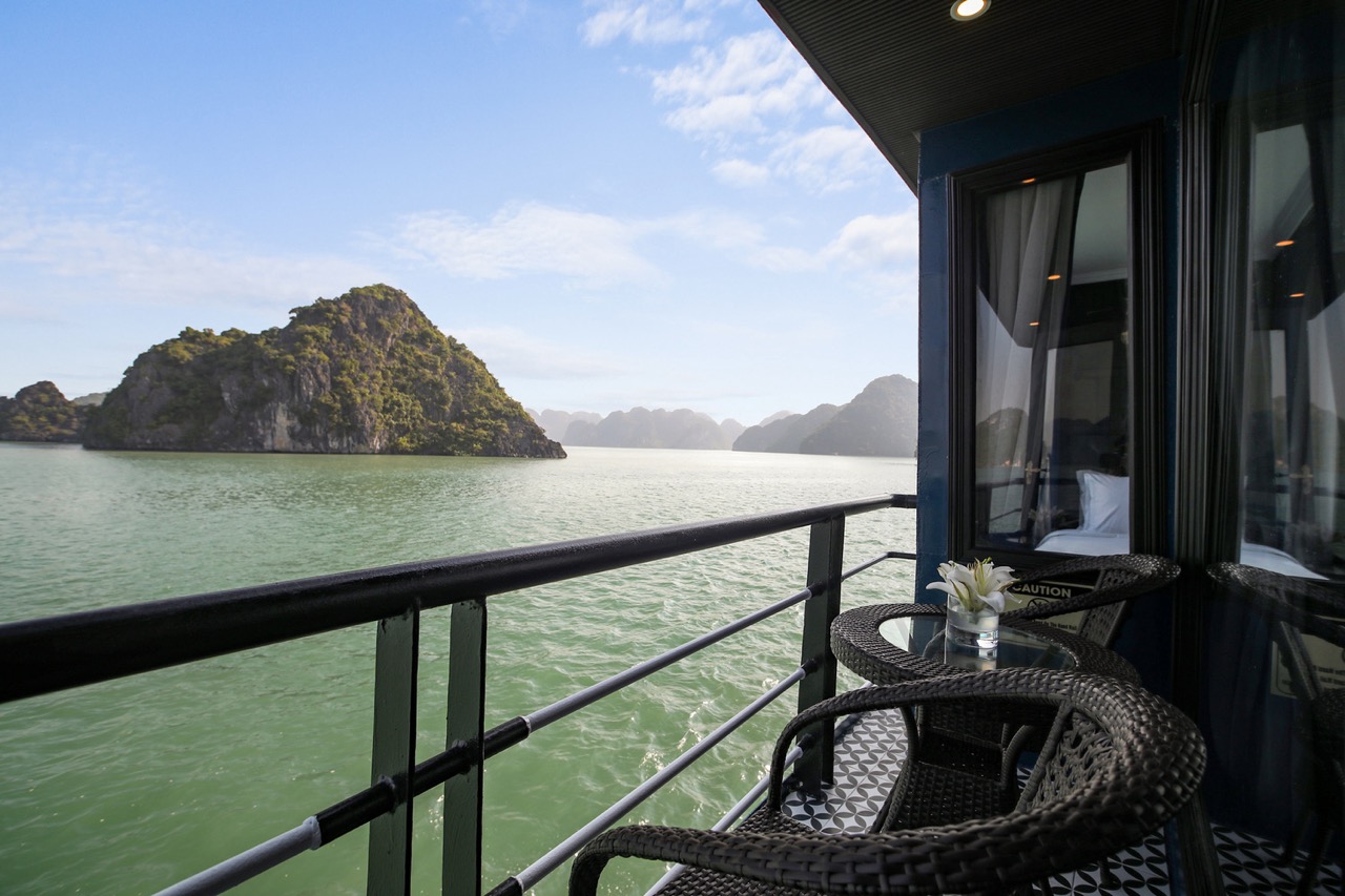 Scenic view of Halong Bay from a luxury cruise balcony with calm waters and lush islands.