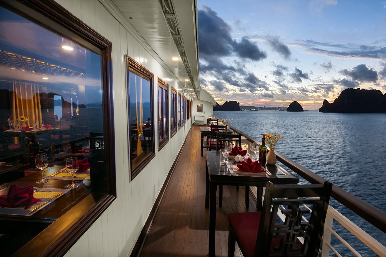 Stunning sunset view from the cruise balcony over Halong Bay, with calm waters and dramatic limeston.