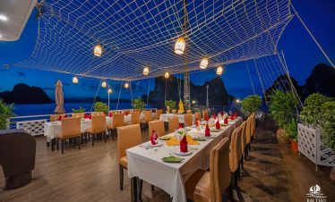 Elegant dining area on Bai Tu Long cruise with sunset views and cozy ambiance.