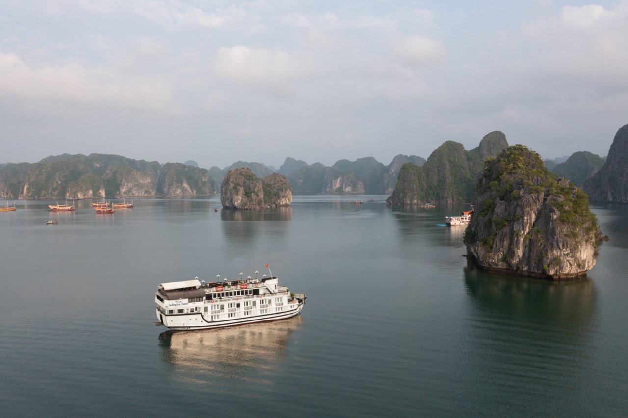 Scenic view of a cruise sailing among limestone karsts in Halong Bay, Vietnam, with calm waters and.