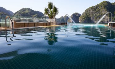 Stunning view of Halong Bay from a cruise balcony with lush islands in the background.