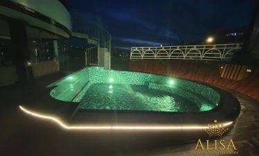 Luxury cruise balcony at night in Halong Bay, showcasing a relaxing hot tub with scenic views and am.