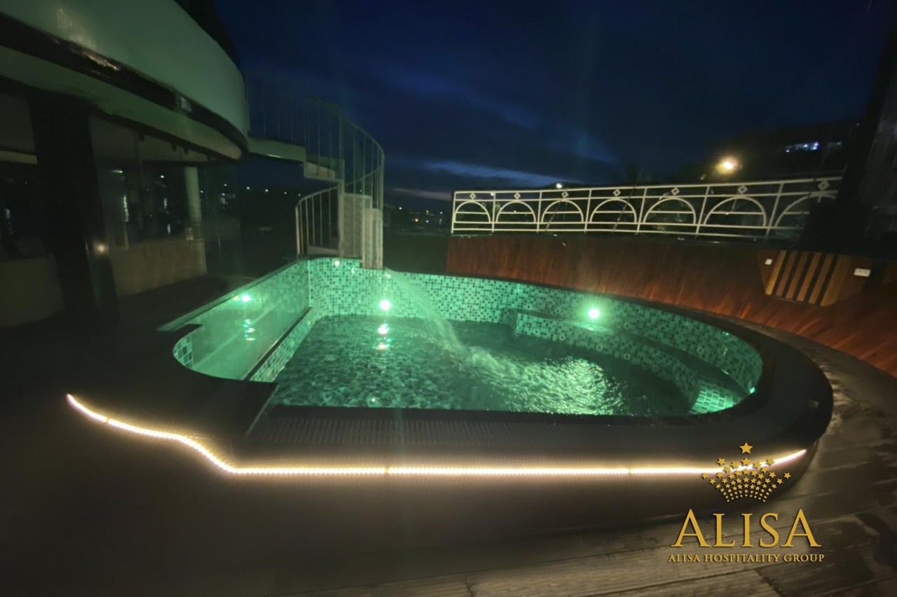 Luxury cruise balcony at night in Halong Bay, showcasing a relaxing hot tub with scenic views and am.