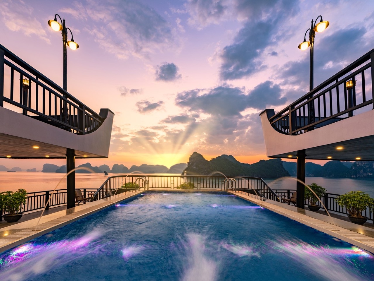 Sunset view from cruise balcony in Halong Bay with scenic limestone islands - ViettrendTour.