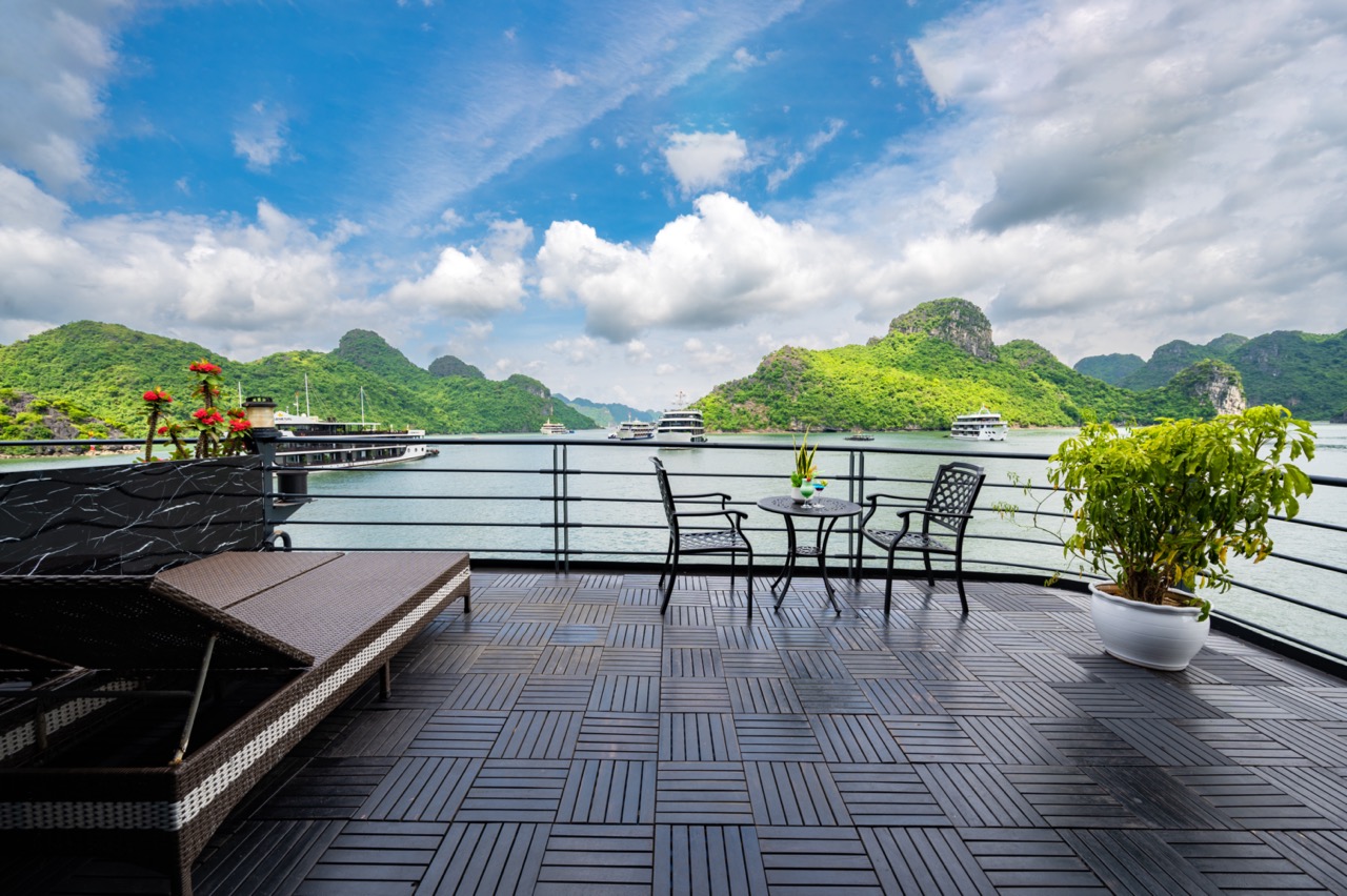 Relaxing cruise balcony overlooking Halong Bay's emerald waters and limestone karsts, perfect for a.