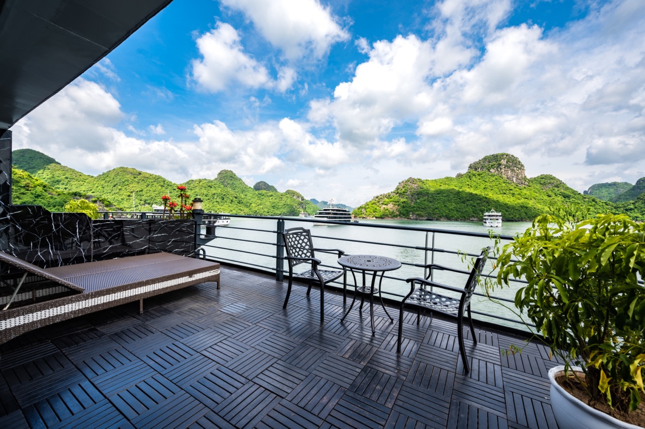 Relaxing Halong Bay cruise balcony with panoramic views of emerald waters and limestone karsts.