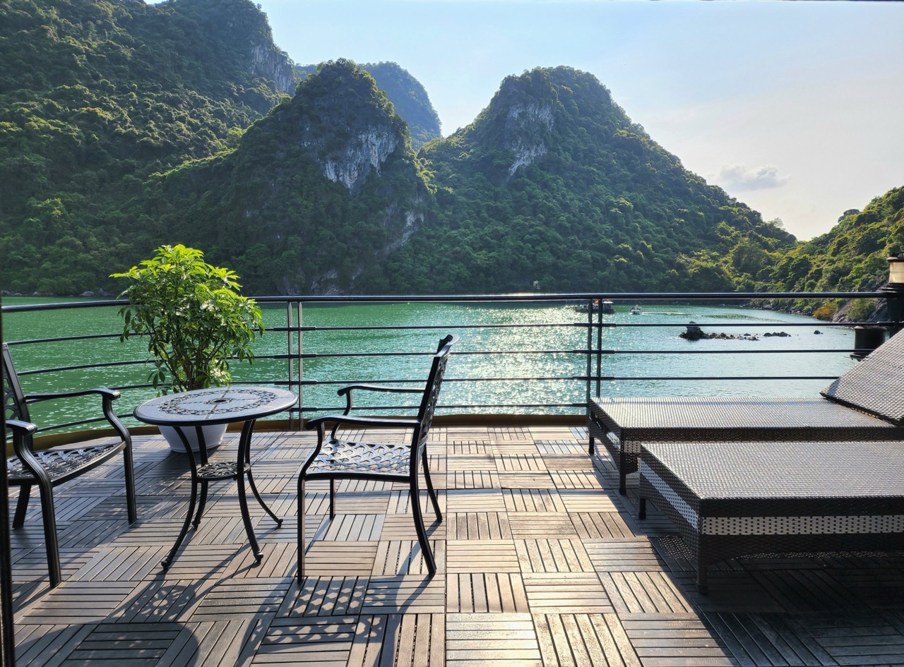 Relaxing cruise balcony overlooking Halong Bay's majestic limestone karsts and emerald waters, perfe.