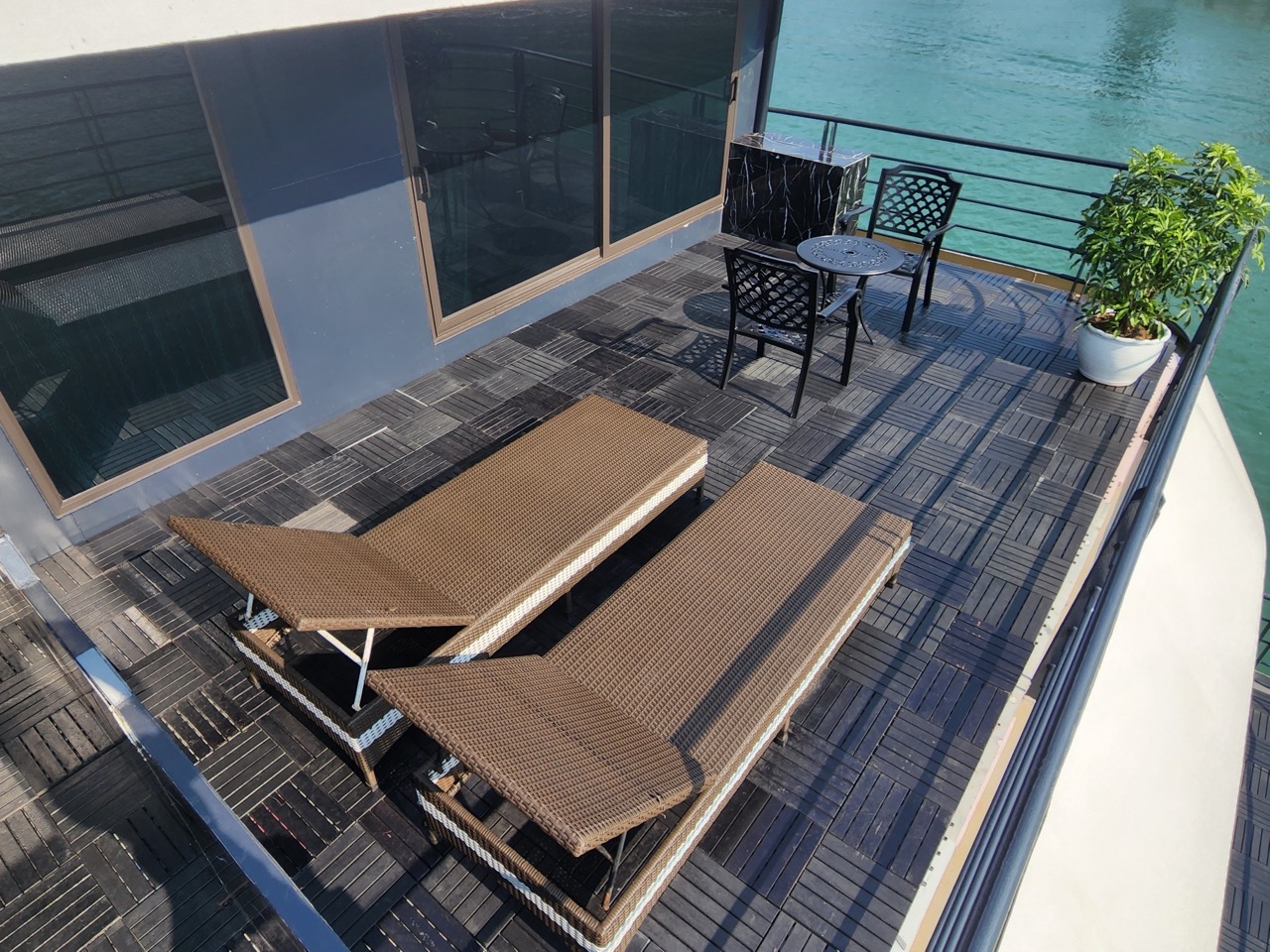 Scenic view from a cruise balcony in Halong Bay featuring outdoor furniture and tranquil waters, per.