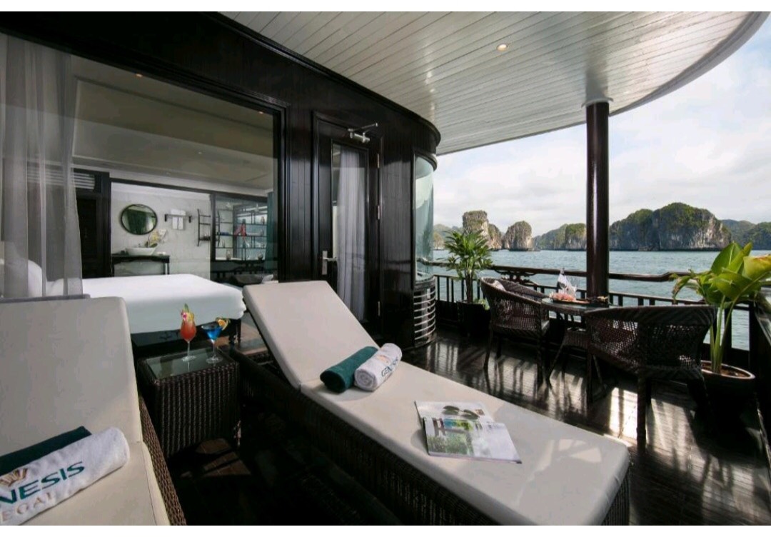 Scenic view of Halong Bay from cruise balcony with relaxing lounge chairs and lush greenery.