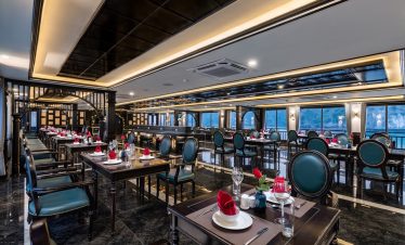 Luxurious cruise dining room with elegant decor and panoramic bay views in Halong Bay.