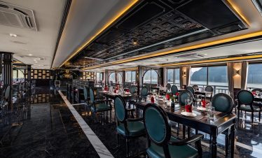 Elegant cruise dining room with panoramic Halong Bay views and sophisticated decor.