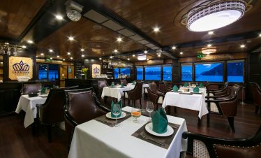 Stunning Halong Bay cruise interior with panoramic views, elegant table settings, and cozy ambiance.
