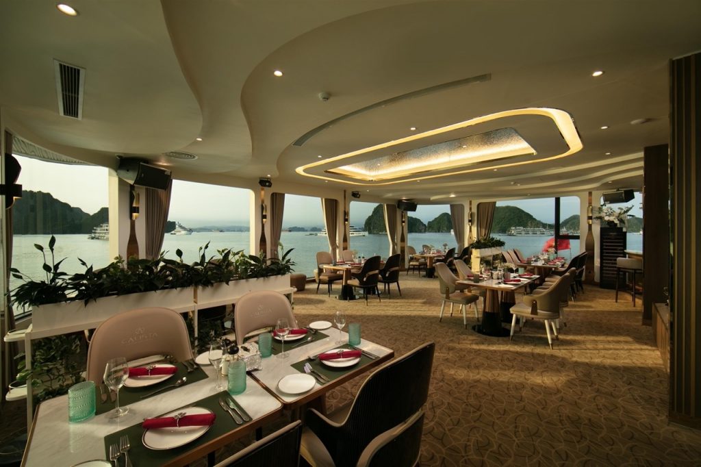 Luxurious cruise dining room overlooking Halong Bay with panoramic sea views and elegant decor.