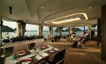 Luxurious cruise dining room overlooking Halong Bay with panoramic sea views and elegant decor.