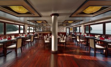 Spacious cruise dining room with large windows overlooking Halong Bay, elegant wooden decor, perfect.