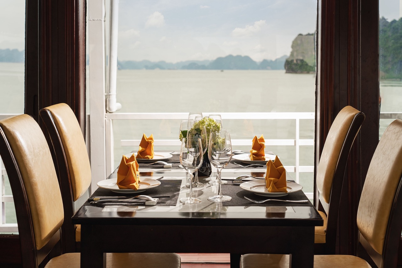 Scenic view of a luxurious dining table on a cruise balcony overlooking Halong Bay, perfect for a re.