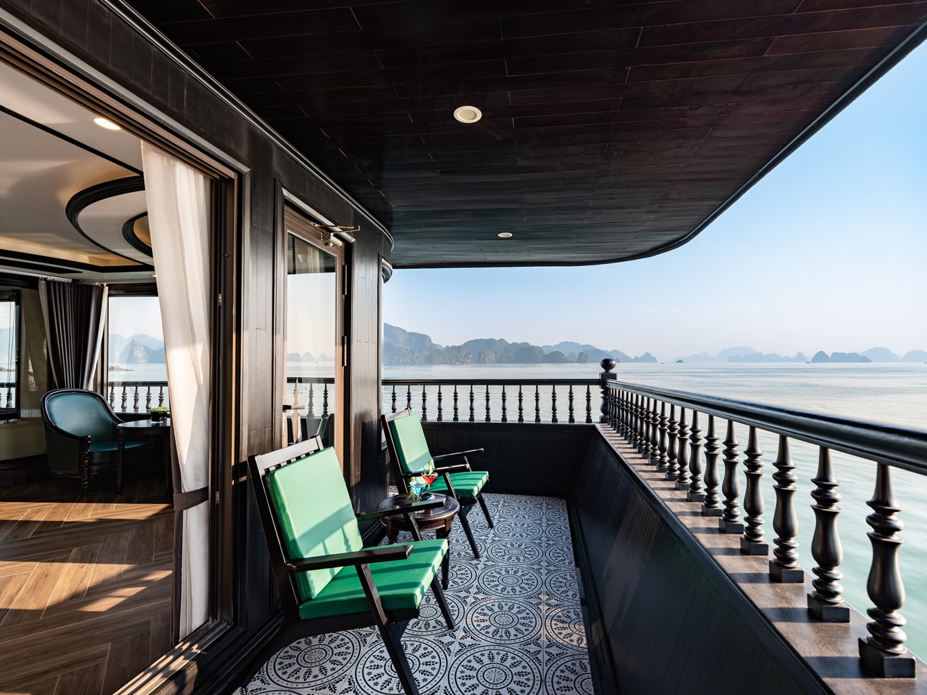 Stunning view from a luxury cruise balcony in Halong Bay, with calm waters and scenic limestone kars.