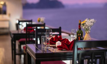 Elegant dining setup with sunset view over Halong Bay, perfect for a romantic cruise experience.