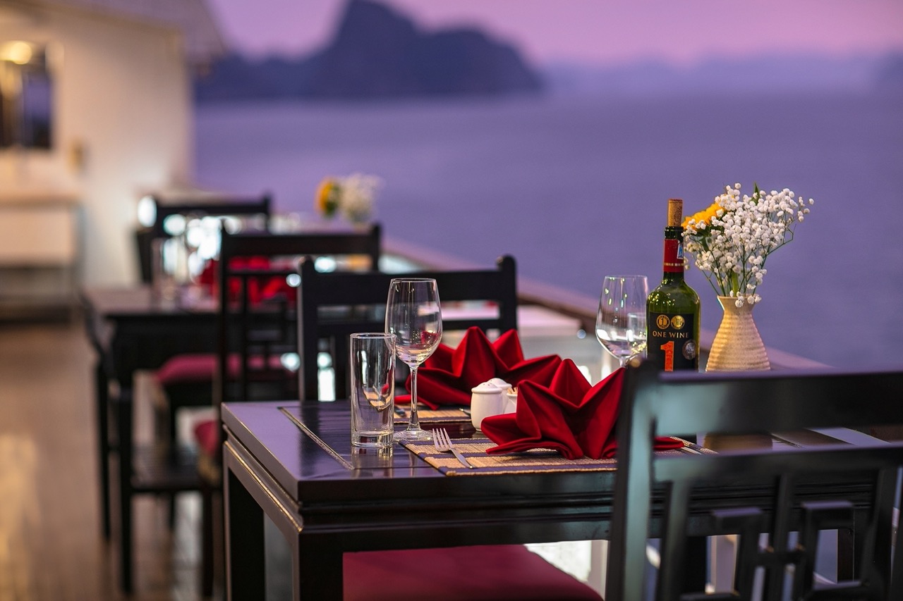 Elegant dining setup with sunset view over Halong Bay, perfect for a romantic cruise experience.
