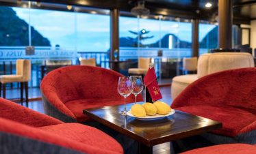Scenic view of Halong Bay from a cruise balcony with cozy seating and sunset ambiance.