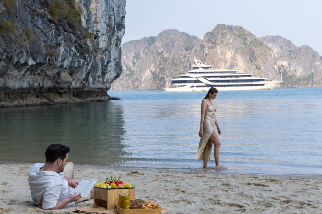 Relaxing scene of a couple enjoying a beach day on Halong Bay with limestone karsts in the backgroun.