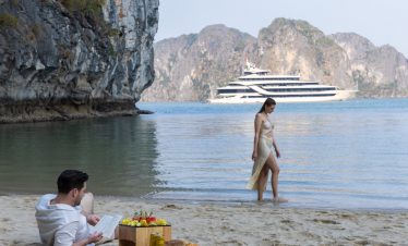 Relaxing scene of a couple enjoying a beach day on Halong Bay with limestone karsts in the backgroun.