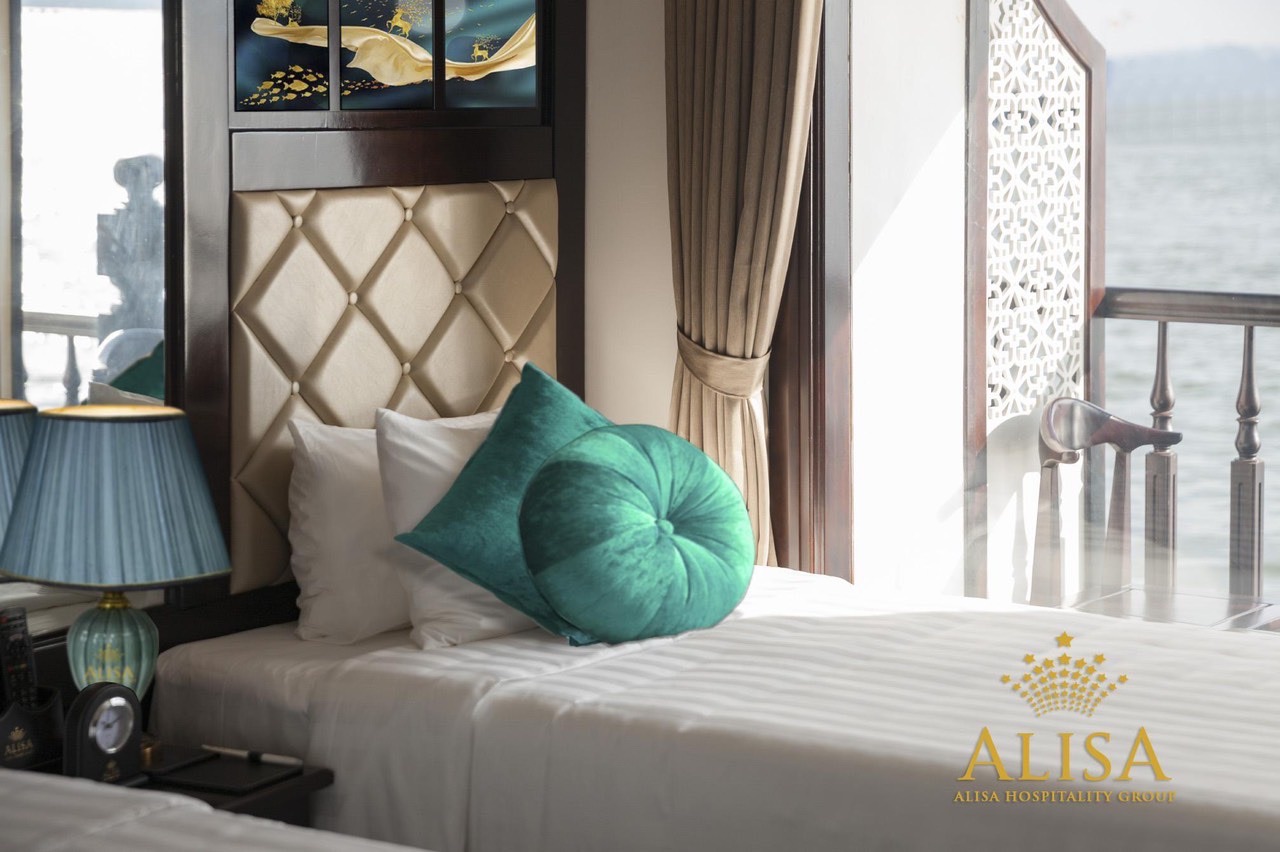 Stunning cruise balcony view of Halong Bay with luxurious bedding and scenic ocean backdrop.