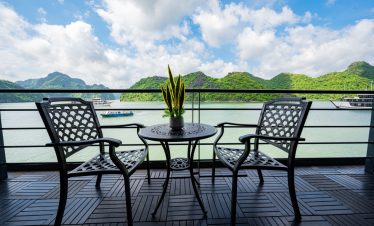 Halong Bay cruise balcony with scenic mountain views and tranquil waters.