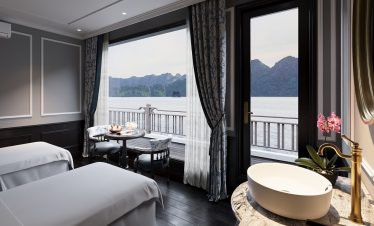 Scenic view of Lan Ha Bay from a luxurious cruise cabin with large windows and elegant decor.