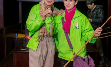 ViettrendTour cultural experience with smiling travelers in traditional attire inside a wooden house.