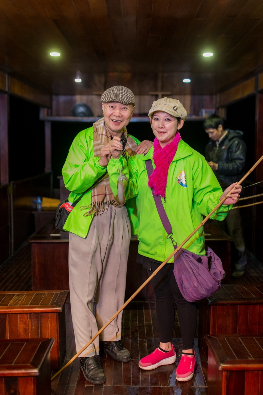 ViettrendTour cultural experience with smiling travelers in traditional attire inside a wooden house.