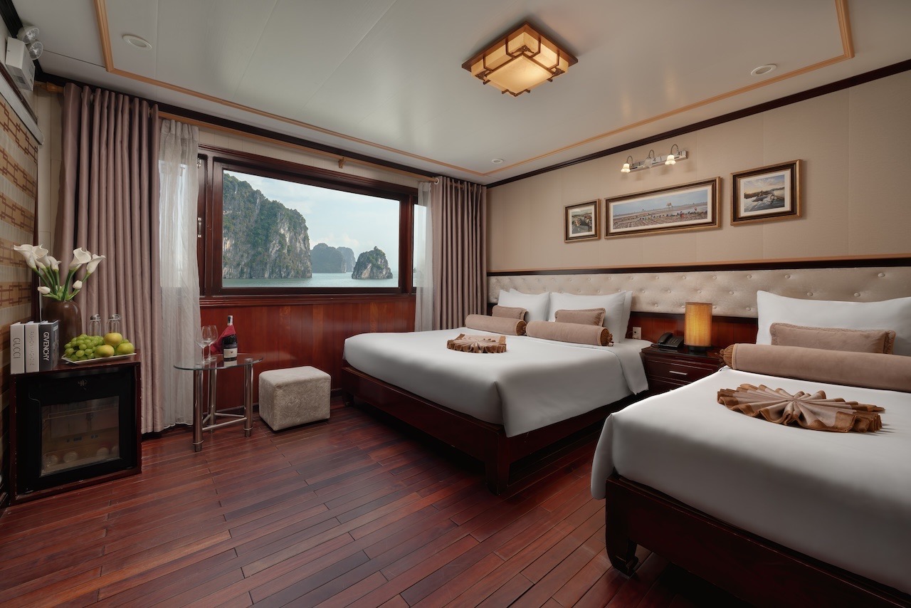 Ocean view cruise cabin with elegant interior and large window overlooking Halong Bay's stunning lim.
