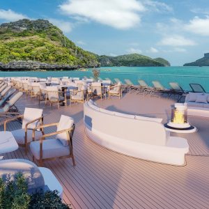 Luxurious oceanview cruise deck with lounge chairs and fire pit in tropical paradise.