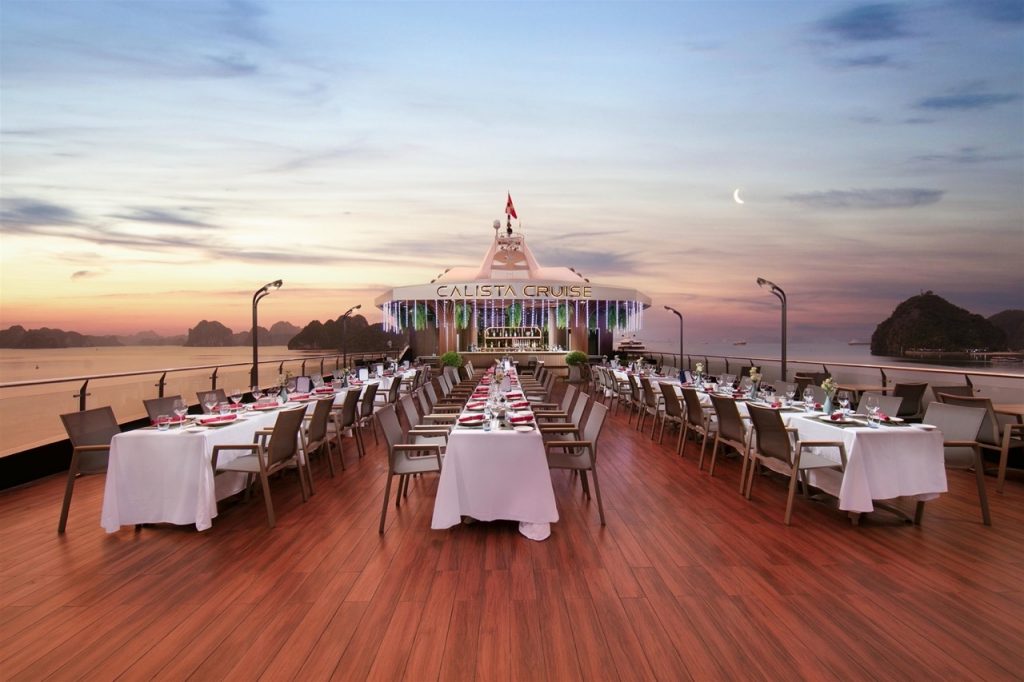 Stunning sunset view from the cruise deck with elegant dining setup in Halong Bay, perfect for a rom.