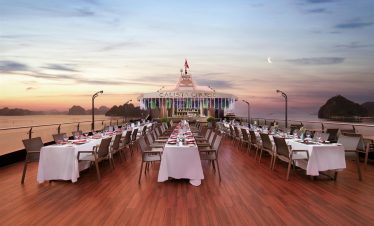 Stunning sunset view from the cruise deck with elegant dining setup in Halong Bay, perfect for a rom.