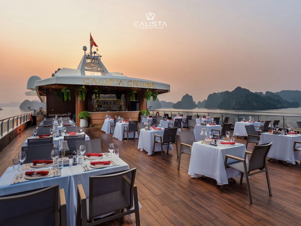 Sunset dining scene on Calista Cruise in Halong Bay with elegant tables and scenic views.