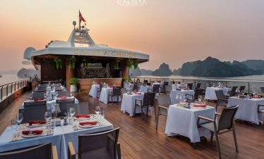 Sunset dining scene on Calista Cruise in Halong Bay with elegant tables and scenic views.