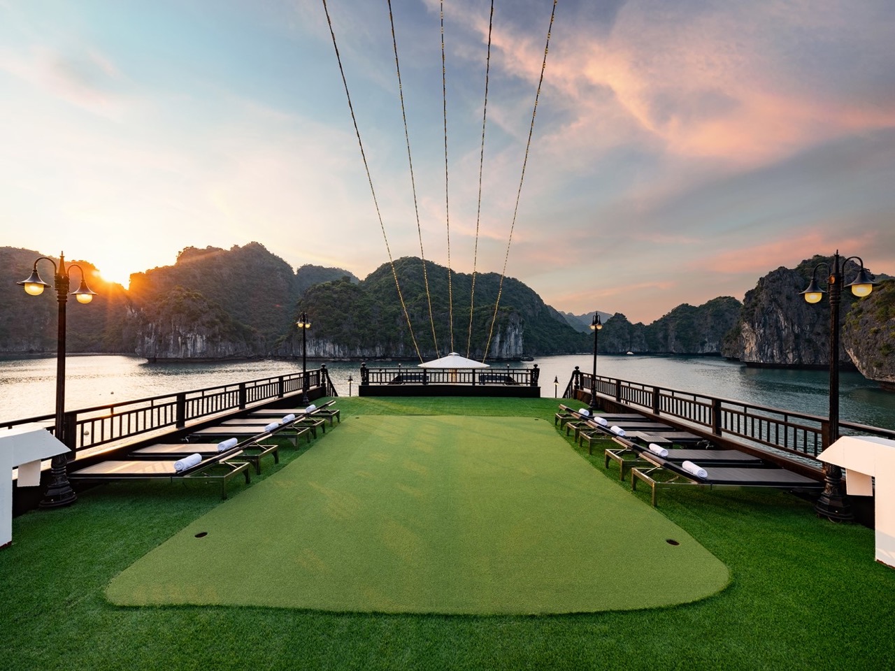 Relaxing cruise balcony overlooking Halong Bay's emerald waters and towering limestone karsts during.