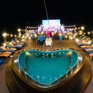 Luxury rooftop party with swimming pool and outdoor entertainment at night, Vietnam tourism.