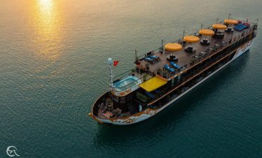 Stunning Halong Bay cruise ship with sun setting over calm waters, perfect for a memorable 2D1N voya.