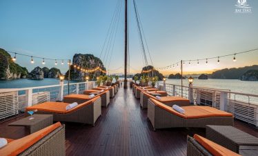 Relaxing cruise balcony with scenic Halong Bay views at sunset.